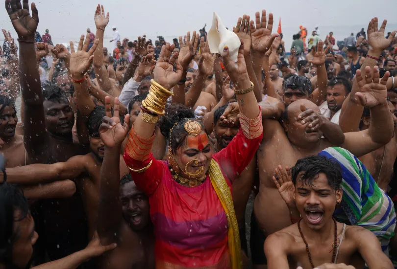 Large crowds of devotees and saints participating in the Shahi Snan ritual at Kumbh Mela 2025, with colorful processions and sacred chants creating a vibrant spiritual atmosphere.